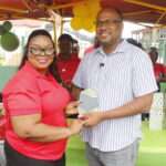 Social Protection Board Operation Manager Mary Baltimore delivering a special token of appreciation to Minister of Social and Urban Transformation Rawdon Turner