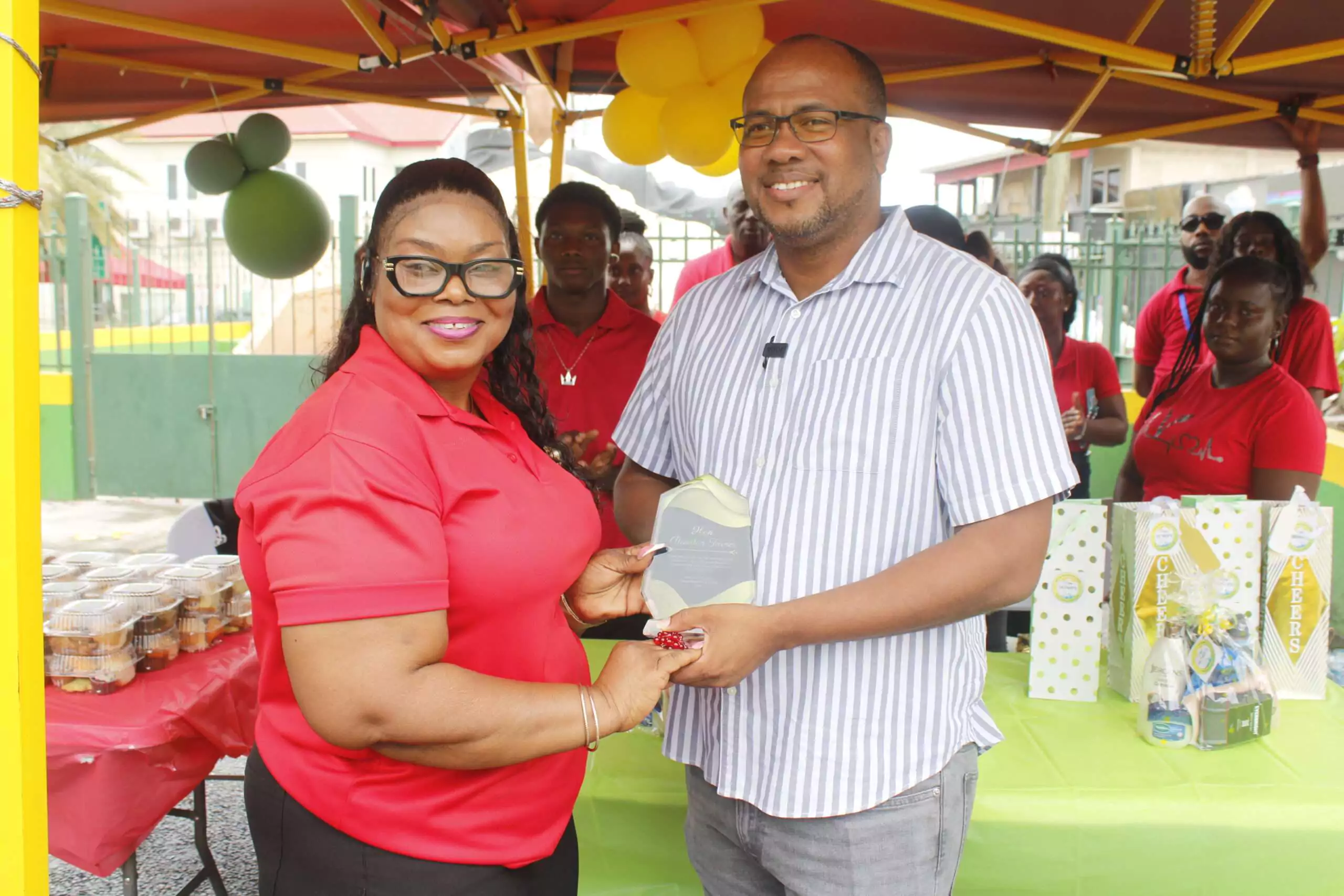 Social Protection Board Operation Manager Mary Baltimore delivering a special token of appreciation to Minister of Social and Urban Transformation Rawdon Turner